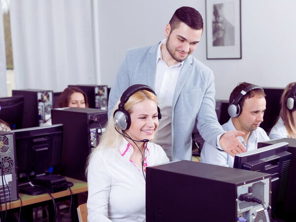 Supervisor guiding agents in a modern call center, with computers and a corporate environment focused on customer service.